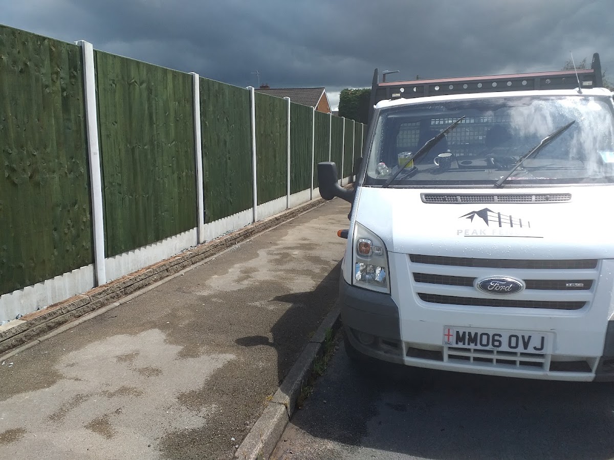Green-stained fencing beside the Peak Fencing work van